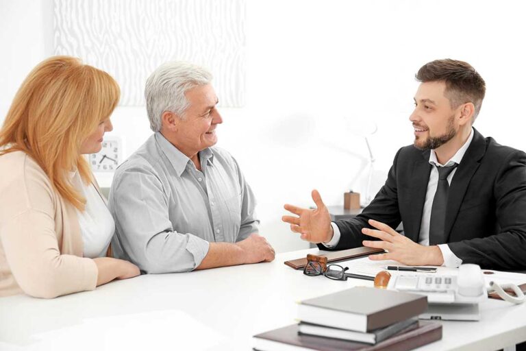 A middle-aged couple reviewing insurance documents together at their kitchen table.
