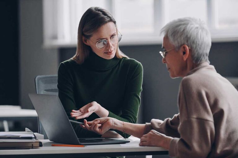 A middle-aged couple and their teenage daughter reviewing documents together at a kitchen table.
